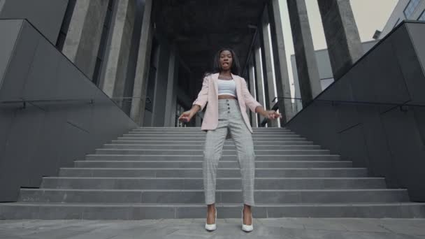 Mladá černoška Dancing Modern Dance On The Stairs. Ona je v obchodním oblečení s vysokými podpatky. Usmívá se a často mění své tváře. — Stock video