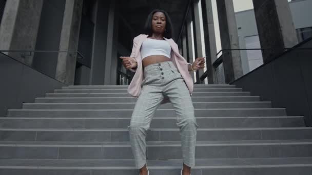 Chica negra bailando danza moderna en las escaleras. Ella está en ropa de negocios. — Vídeo de stock