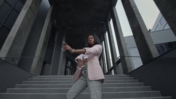 Jong zwart meisje dat op de trappen van het gebouw staat. Ze legde haar handen op haar borst. Ze is serieus.. — Stockvideo