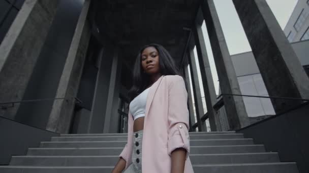 Chica Negra de pie en las escaleras del edificio. Ella está elegantemente vestida con estilo de negocios. — Vídeo de stock