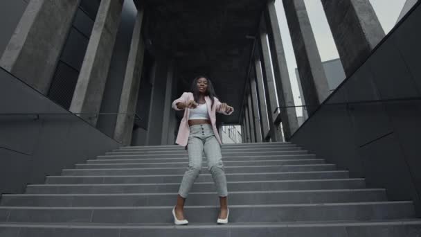 Young Black Girl Dancing Modern Dance On The Stairs (en inglés). Ella está en ropa de negocios con tacones altos. Ella aplaude sus manos. — Vídeo de stock