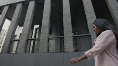 Güzel Siyah Kız Sokakta Yürüyor. Pembe Ceketli Uzun Saçlı Güzel Kız Gri Binayı Geçiyor.