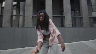 Sokakta dans eden siyah kız. Uzun binalarının arkasında. Modern danslar. Çok hızlı hareket ediyor..