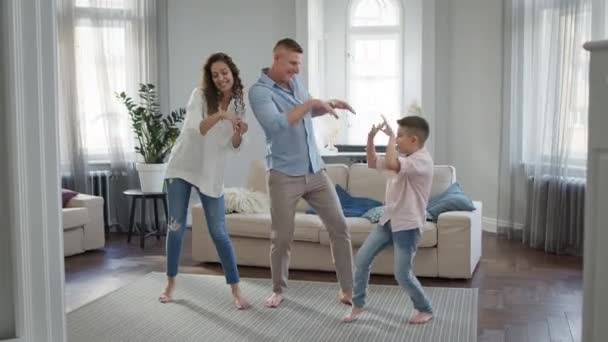 Vrije tijd jong gezin vader moeder en zoon dansen in de kamer op blote voeten. — Stockvideo