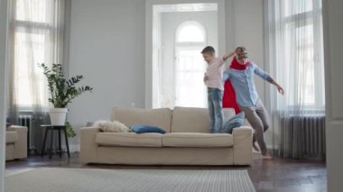 Baba ve Oğul apartmanda oyun oynuyorlar. Babam kırmızı pelerinli ve gözlüklü..