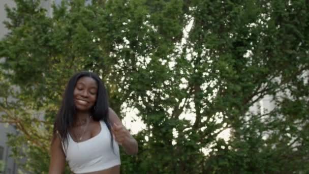 若い黒の女の子は緑の木の背景にモダンダンスを踊る. — ストック動画