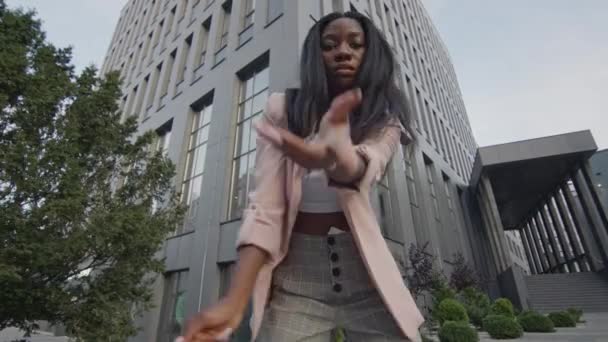 Όμορφο μαύρο κορίτσι που χορεύει στο δρόμο. Πίσω από τα ψηλά κτίρια. Σύγχρονοι χοροί. — Αρχείο Βίντεο