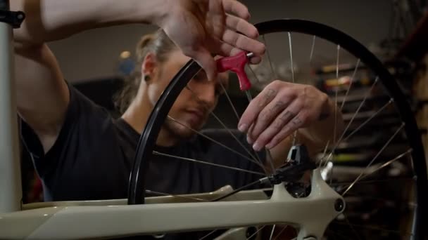 Maître installe la roue sur le vélo. bel homme dans l 'atelier. — Video