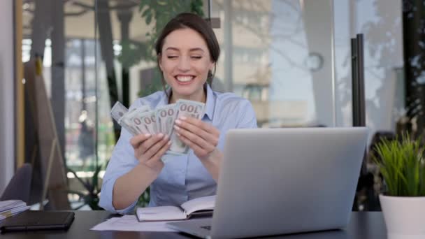 Mladá dívka kancelářská pracovník sedí u stolu. Počítá peníze a úsměvy. — Stock video
