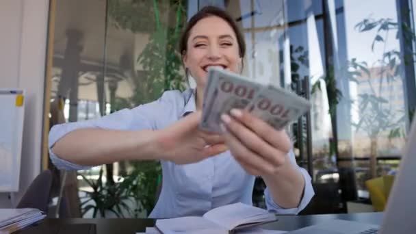 Ung flicka kontor arbetare sitter vid bordet. Hon räknar pengarna och ler. Spridning av alla pengar. Lycklig flicka. — Stockvideo