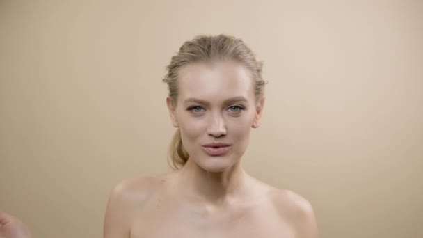 Visage de jeune modèle élégant avec une belle peau. Jolie blonde touche ses joues avec ses mains. — Video