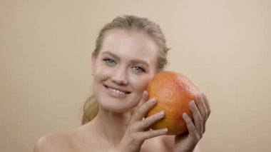 Model In Studio Poz. Uzun Saçlı Genç Sarışın Greyfurt Tutuyor.