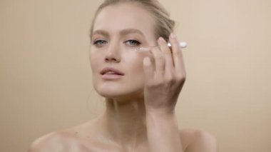 Güzel ciltli şık genç bir mankenin yüzü. Yüzüne kozmetik ilacı damlatıyor..