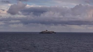 Sakin su ve kasvetli bulutlarla izole edilmiş sahne, kaygı verici bulutlar ve yansıtıcı suların ortasındaki huzurlu feribot.