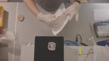 Eldivenli eller diş izi tepsisini hazırlıyor, steril zarfı kalıbın üzerine katlıyor, yumuşak ışık altında yüzeyi inceliyor.,