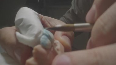 Kapalı fırça seramik diş, narin pigment ve leke seramist tarafından uygulanır, küçük oyulmuş protez ellerde tutulur.,