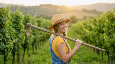 Günbatımında bağda çapa taşıyan beyaz kadın şarap tüccarı, üzümlerin üzerinde altın ışık, hasır şapka ve kot, sıcak hasat havası,