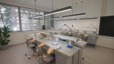 Mikroskop, ergonomik sandalyeler, yukarıdaki lambalar ve organize tepsilerle donatılmış güneş ışığı laboratuvarı.