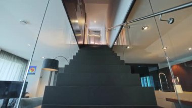 Modern çatı katında dramatik cam merdiven açık oturma odası doğal açık siyah basamaklar, sinema korkulukları ile dolu.