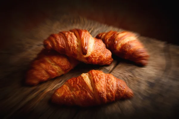 Croissant on wooden table - blurred style photo — Stock Photo, Image