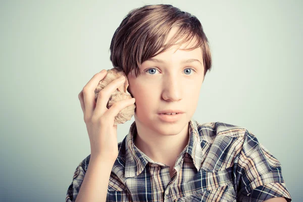 Boy listening to a seashell — Stock Photo, Image