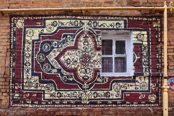 Painted rug on a brick wall — Stock Photo, Image