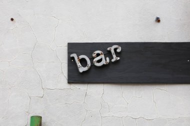 Beyaz duvarda eski bar tabelası