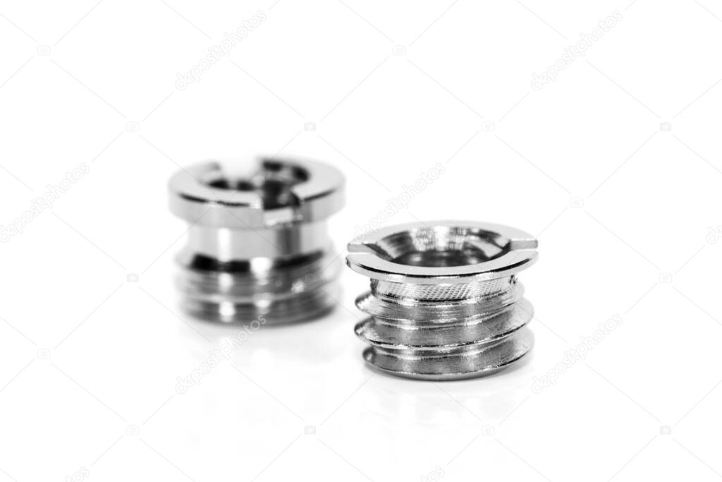 Close up shot of two shiny threaded metal inserts on white background