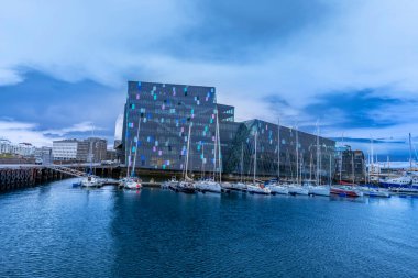 REYKJAVIK, ICELAND - 4 Haziran 2021: Mavi saatte Harpa Konser Salonu manzarası. Bina, İzlanda 'nın bazalt manzarasından esinlenilmiş belirgin renkli bir cam cephe içeriyor..