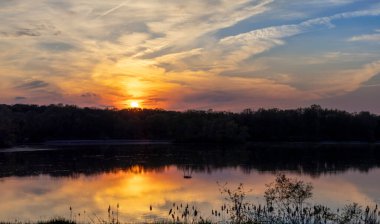 Gölün üzerinde dramatik bulutlarla gün batımı