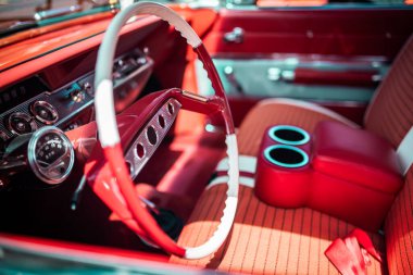 Close up shot of steering wheel and interior view of a red vintage muscle car