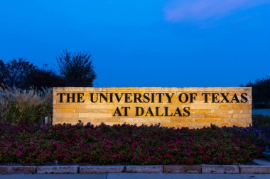 Dallas, TEXAS, ABD, Kasım, 16, 2025: Teksas Üniversitesi alacakaranlık gökyüzüne karşı ışıklandırılmış çiçekler ve yapraklarla birlikte