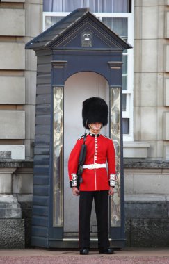 One soldier stand guard outside Buckingham Palace in London clipart