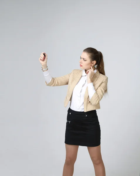 Giovane donna con penna su sfondo grigio — Foto Stock