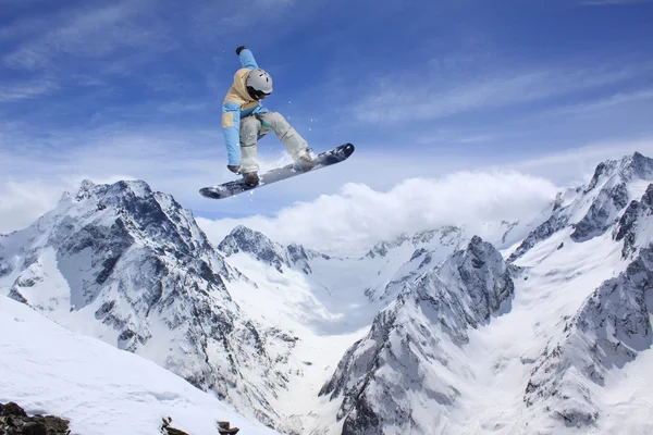 Lentävä lumilautailija vuorilla. Äärimmäinen urheilu. — kuvapankkivalokuva