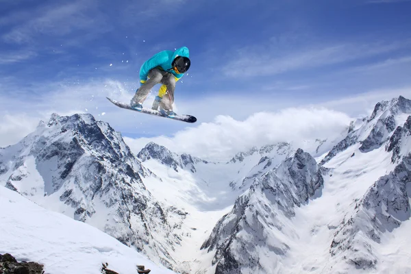 Um snowboarder voador nas montanhas. Desporto extremo. — Fotografia de Stock