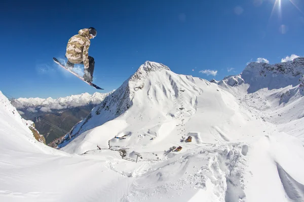 Um snowboarder voador nas montanhas. Desporto extremo. — Fotografia de Stock