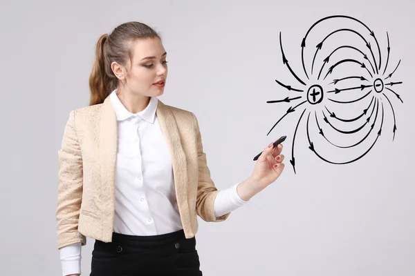 Jeune femme, professeur de physique dessine un diagramme du champ électrique — Photo