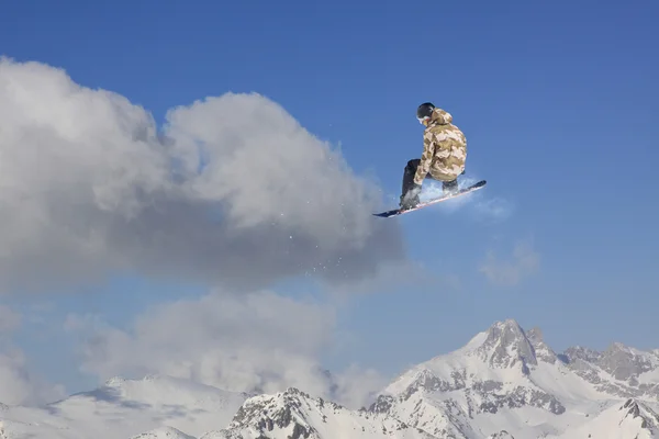 Um snowboarder voador nas montanhas. Desporto extremo. — Fotografia de Stock