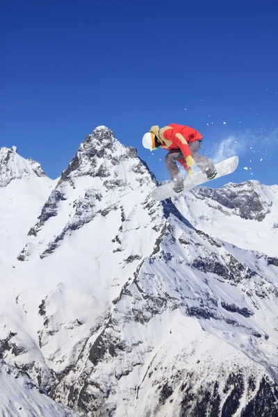 Cavaleiro de snowboard pulando em montanhas. Freerida extrema de snowboard . — Fotografia de Stock