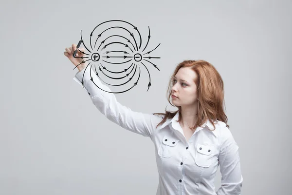 Mladá žena, učitel fyziky nakreslí Schéma elektrického pole — Stock fotografie