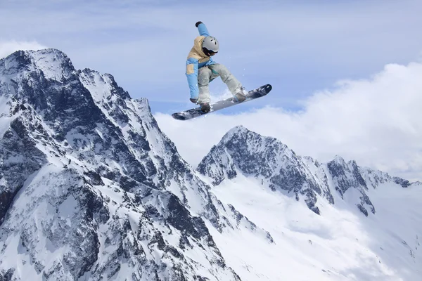 Snowboard jezdec skákat na horách. Extrémní snowboard freeride sport. — Stock fotografie