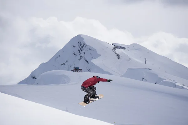 Cavaleiro de snowboard pulando em montanhas. Esporte de freeride de snowboard extremo. — Fotografia de Stock