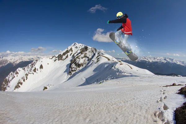 Jeździec na snowboardzie skaczący po górach. Ekstremalne snowboard freeride sportu. — Zdjęcie stockowe