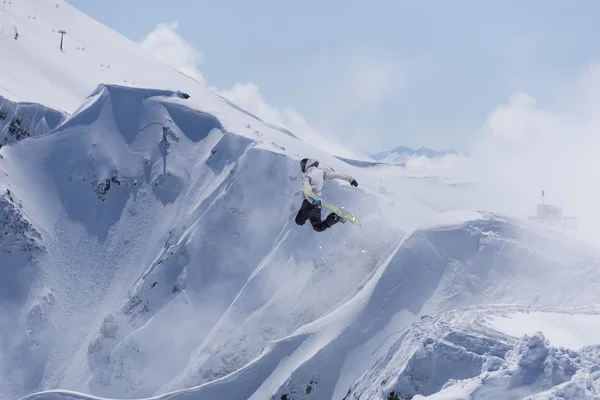 Сноубордист прыгает по горам. Экстремальный фрирайд на сноуборде. — стоковое фото