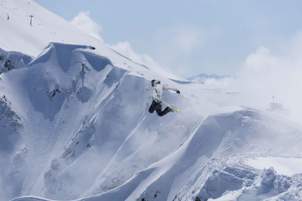 Cavaleiro de snowboard pulando em montanhas. Esporte de freeride de snowboard extremo. — Fotografia de Stock