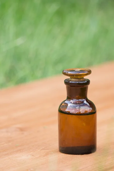 Little brown bottle on booden board and grass — Stock Photo, Image