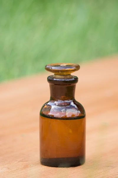 Pequeña botella marrón en booden tablero y hierba — Foto de Stock