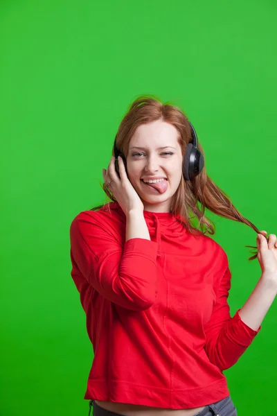 Mulher ouvindo música em fones de ouvido, fundo verde — Fotografia de Stock