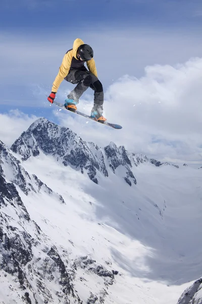 Cavaleiro de snowboard pulando em montanhas. Esporte de freeride de snowboard extremo. — Fotografia de Stock